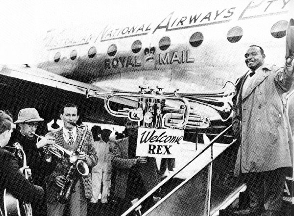 Jazz musician Rex Stewart welcomed off plane in Melbourne by trumpter Roger Bell and other musicians in 1949